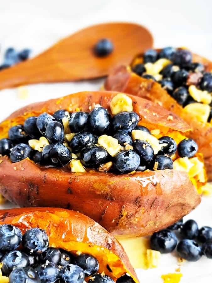 baked stuffed sweet potatoes up close with blueberries, walnuts, and cinnamon